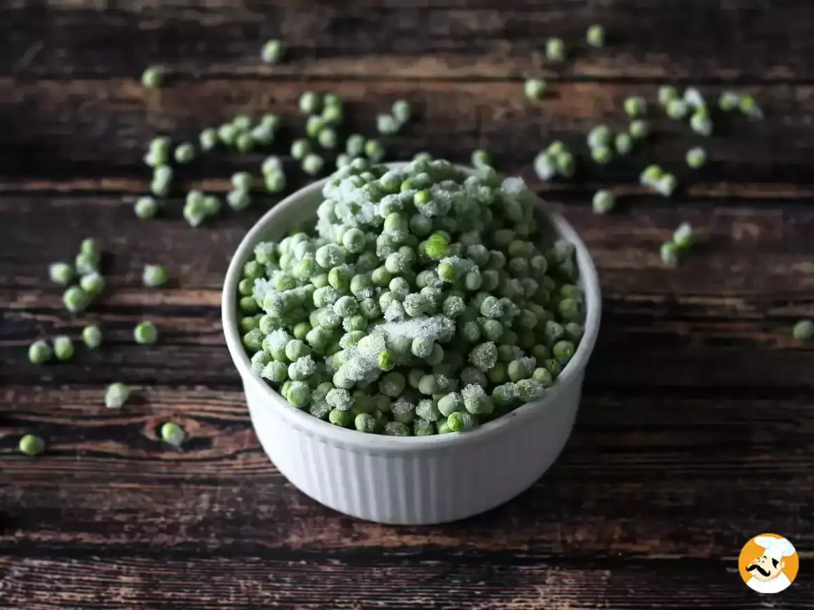 Un cuenco blanco lleno de guisantes congelados, perfecto para tus próximas recetas con guisantes congelados.
