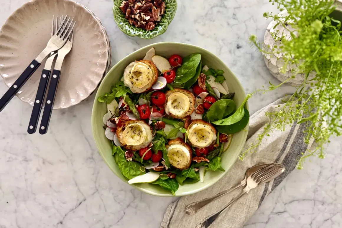 En härlig somrig mat-upplevelse med en fräsch sallad toppad med gratinerad getost på rostat bröd, körsbärstomater, rädisor och nötter.