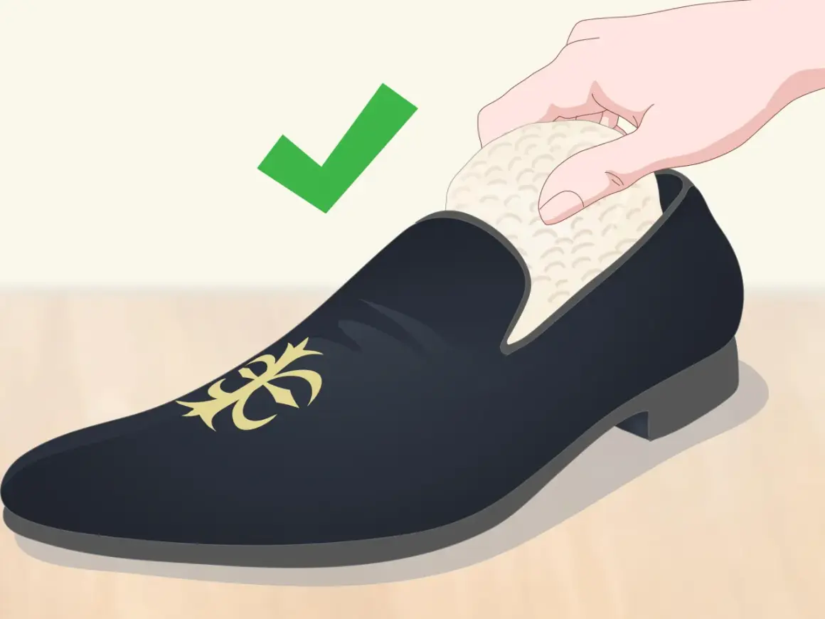 Une main insère un embauchoir dans une chaussure de ville noire ornée d'un motif doré. La mise en forme des chaussures est essentielle pour leur longévité. ✅