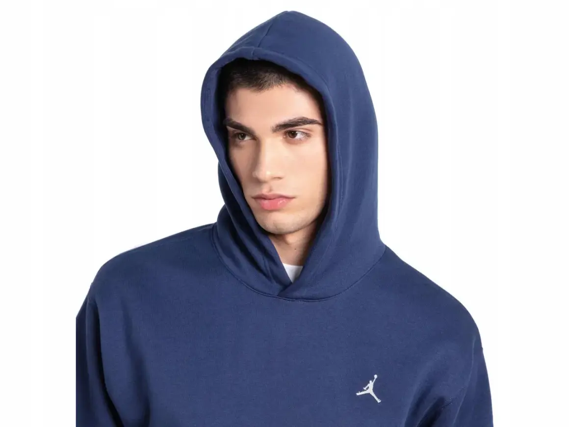 Młody mężczyzna w granatowej bluzie z kapturem Nike Jordan, z małym białym logo Jumpmana na piersi.