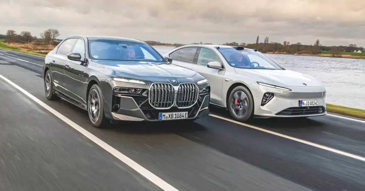 Dwa nowoczesne sedany, w tym chińskie BMW, pędzą po mokrej drodze.