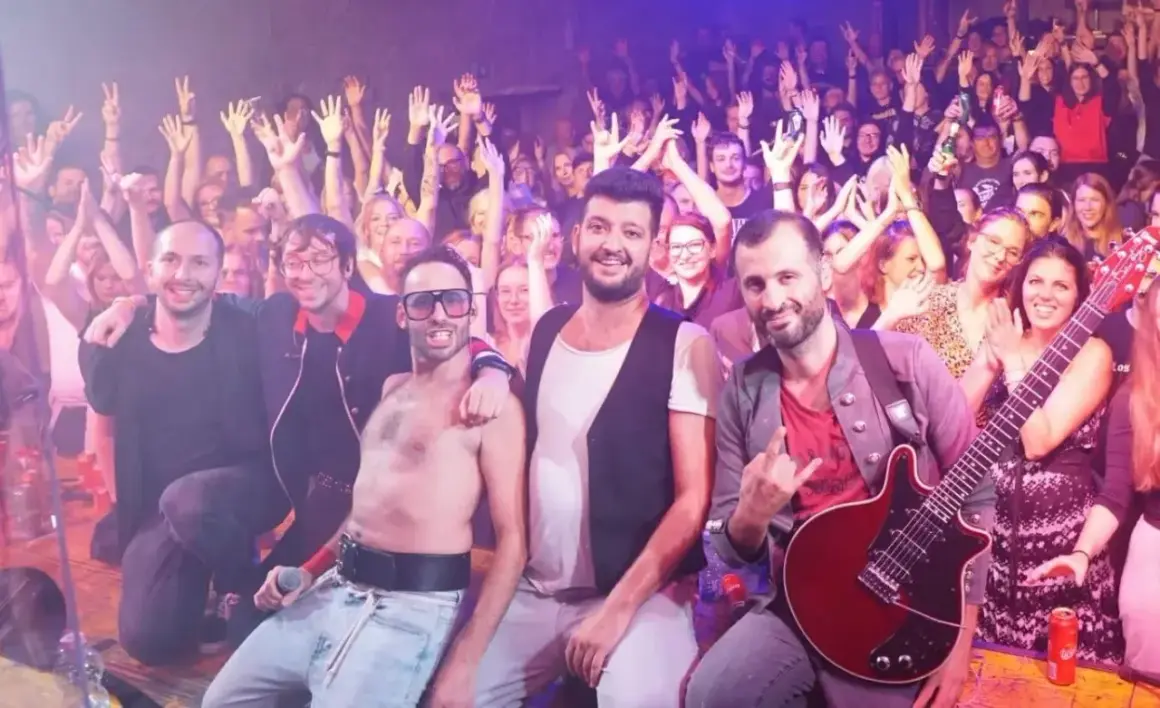 La cover band dei Queen infiamma il pubblico con un'energia contagiosa. La folla alza le mani in segno di approvazione.