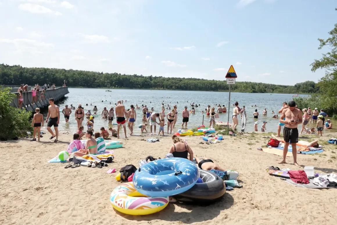 Tłum ludzi odpoczywa nad jeziorem w Wielkopolsce. Kąpielisko tętni życiem, w wodzie i na plaży widać wielu kąpiących się i plażowiczów.