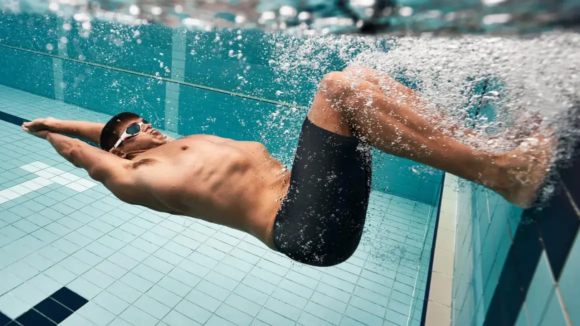 Schwimmer mit Brille und Badehose treibt unter Wasser. Das extensives intervalltraining fordert ihn.