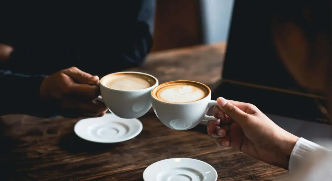 Dos tazas de café humeante, una con arte latte. El café es bueno para la concentración y el disfrute.