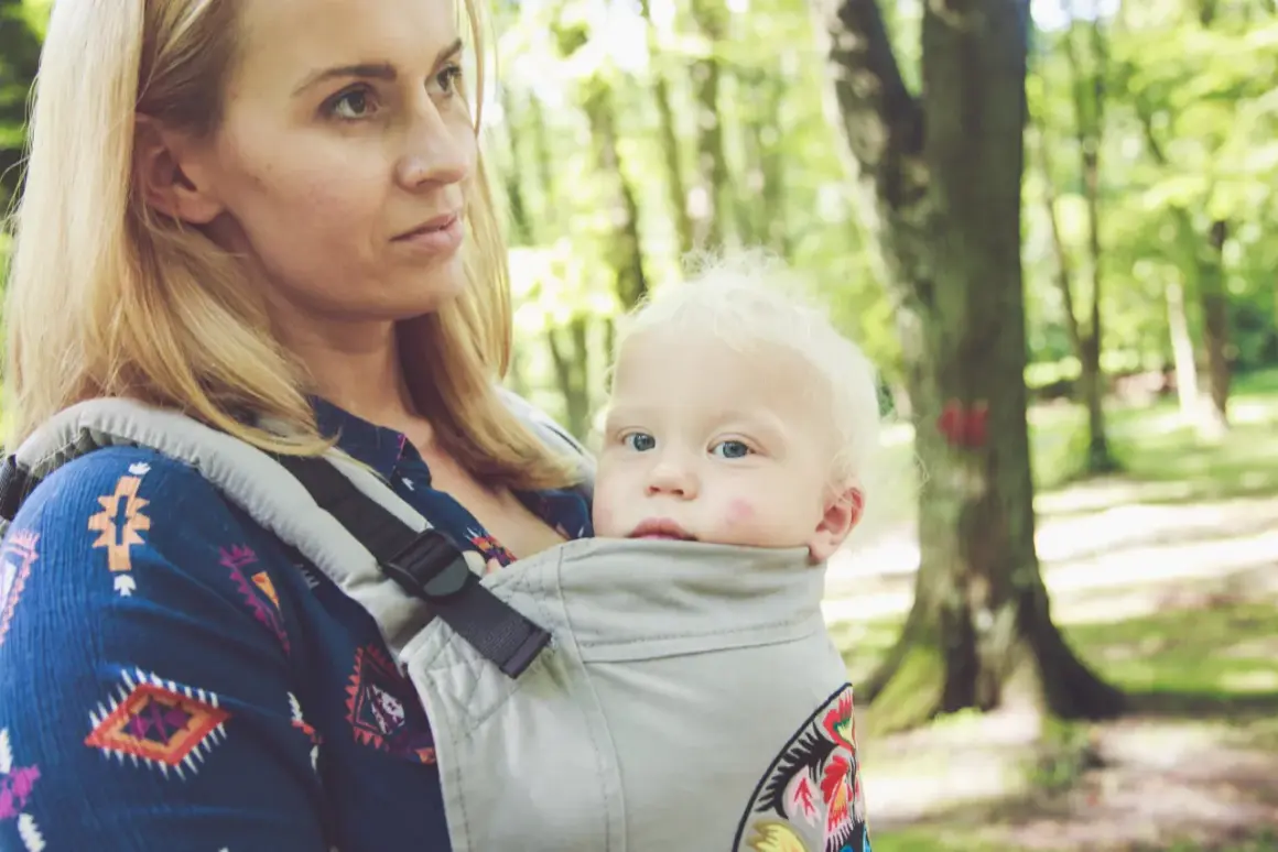 Mama z dzieckiem w nosidle w lesie. Zastanawiasz się, jakie nosidełko wybrać? To wygodne rozwiązanie na spacery.