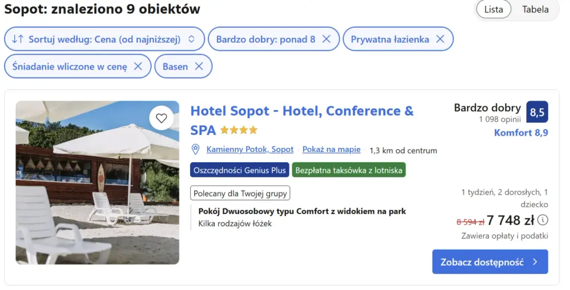 Białe leżaki i parasole na plaży przed budynkiem hotelu.