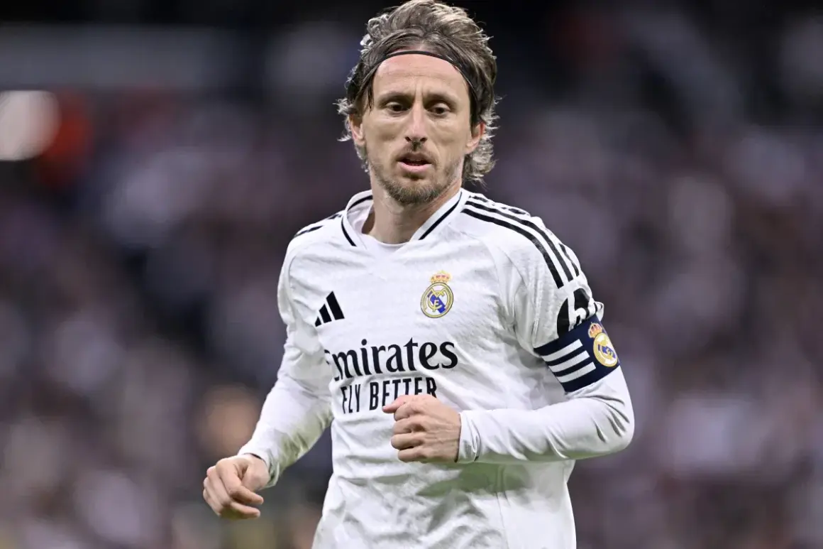 Chorwacki piłkarz Luka Modrić w białej koszulce Realu Madryt, z opaską kapitana na ramieniu, skupiony na grze.