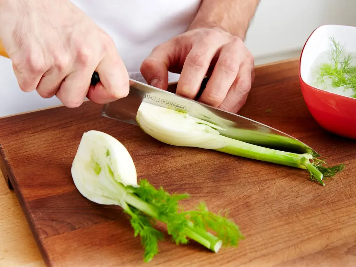 Hände schneiden Fenchel für leckere Fenchel Rezepte. Ein Teil liegt auf dem Holzbrett, ein anderer in einer roten Schüssel mit Wasser.