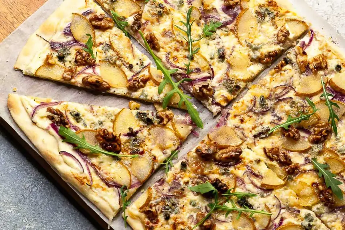 Ein köstlicher flammkuchen vegetarisch mit Birnenspalten, roten Zwiebeln, Walnüssen und Rucola.