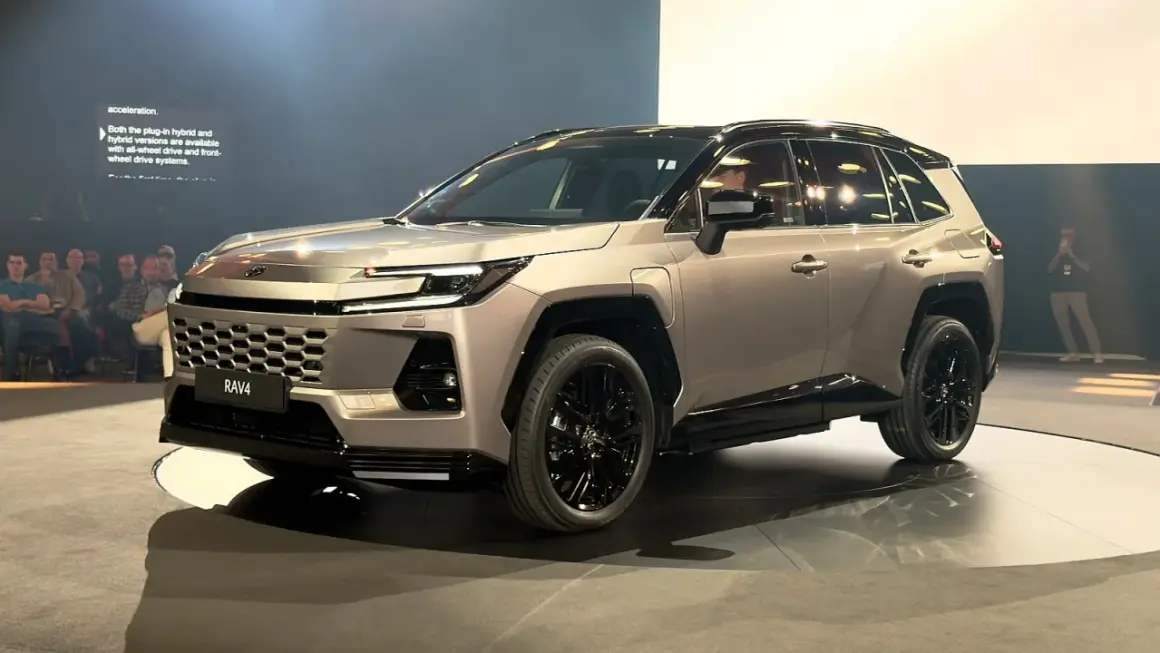 Nowy Toyota RAV4 2026 w kolorze szampańskim, z czarnymi felgami i przyciemnianymi szybami, prezentowany na scenie.