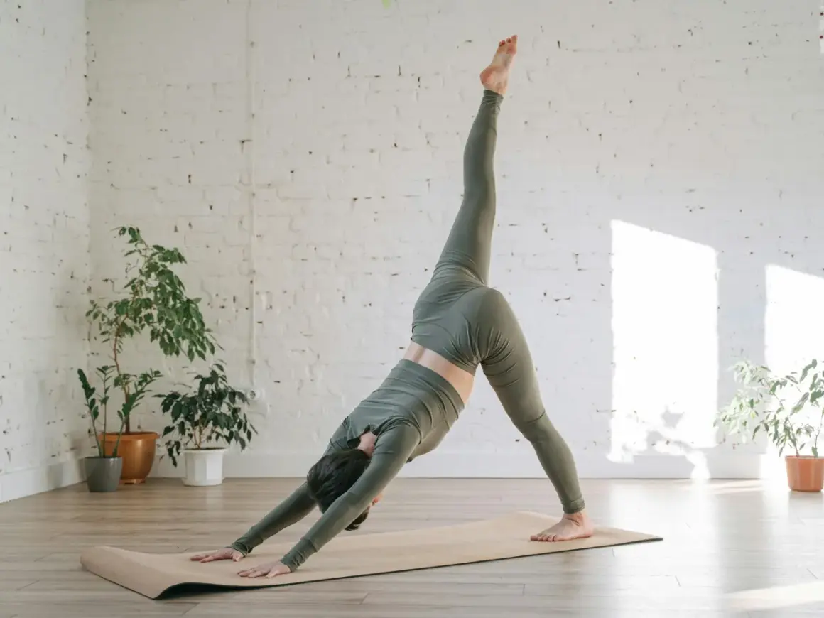 Mujer en postura de yoga de tres patas, explorando el vinyasa significado. El flujo dinámico se refleja en su movimiento.