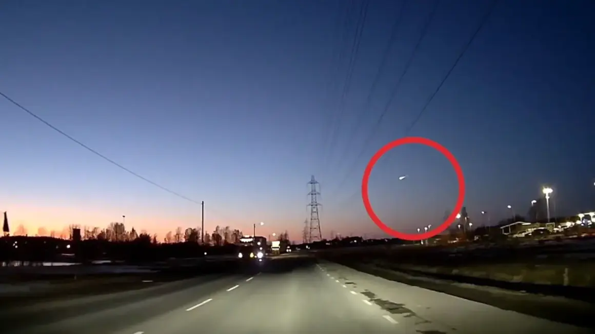 En ljusstark meteor syns på den mörka himlen över en väg i Sverige.