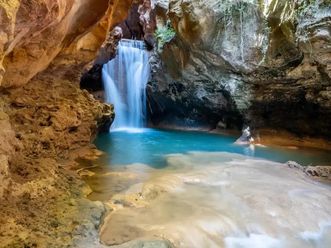 Cascada en una cueva, ideal para excursiones cerca de Zaragoza con agua cristalina y formaciones rocosas.