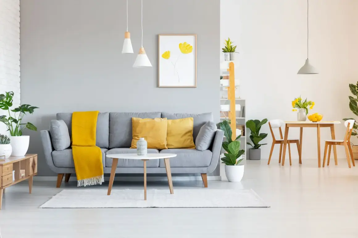 Graue wandfarben im Wohnzimmer harmonieren perfekt mit gelben Akzenten auf dem Sofa und dem Essbereich.