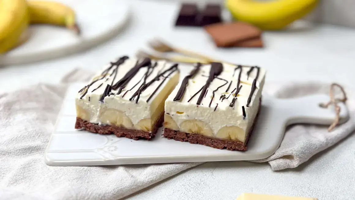 Zwei Stücke Bananensplit Torte mit Schokoladenboden, Bananenscheiben und cremiger Füllung, garniert mit Schokoladensauce.
