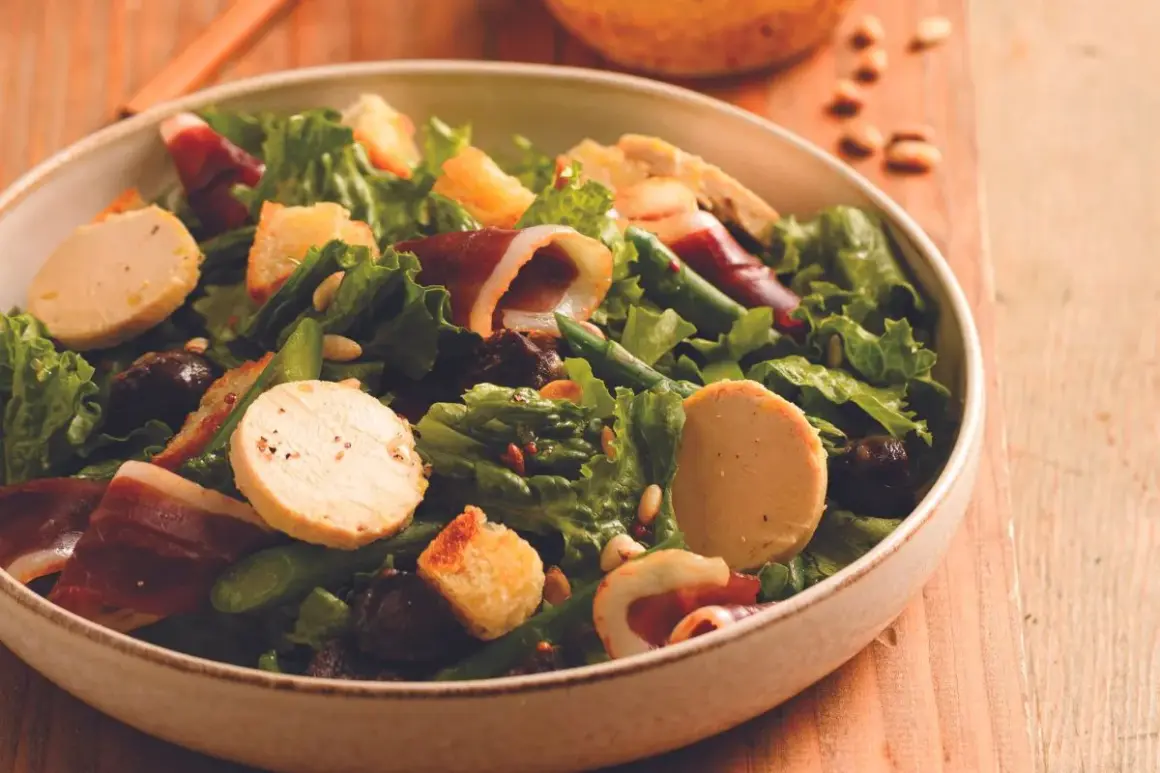 Salade périgourdine : foie gras, magret fumé, asperges vertes, croûtons et olives noires dans un bol.