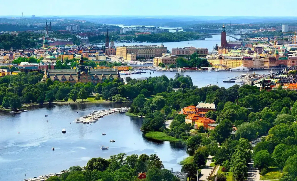 Widok na miasto z wodą i zielenią. W oddali widać budynki, a na pierwszym planie rzekę z łodziami. To piękny krajobraz, jakby z lotniska Nyo.