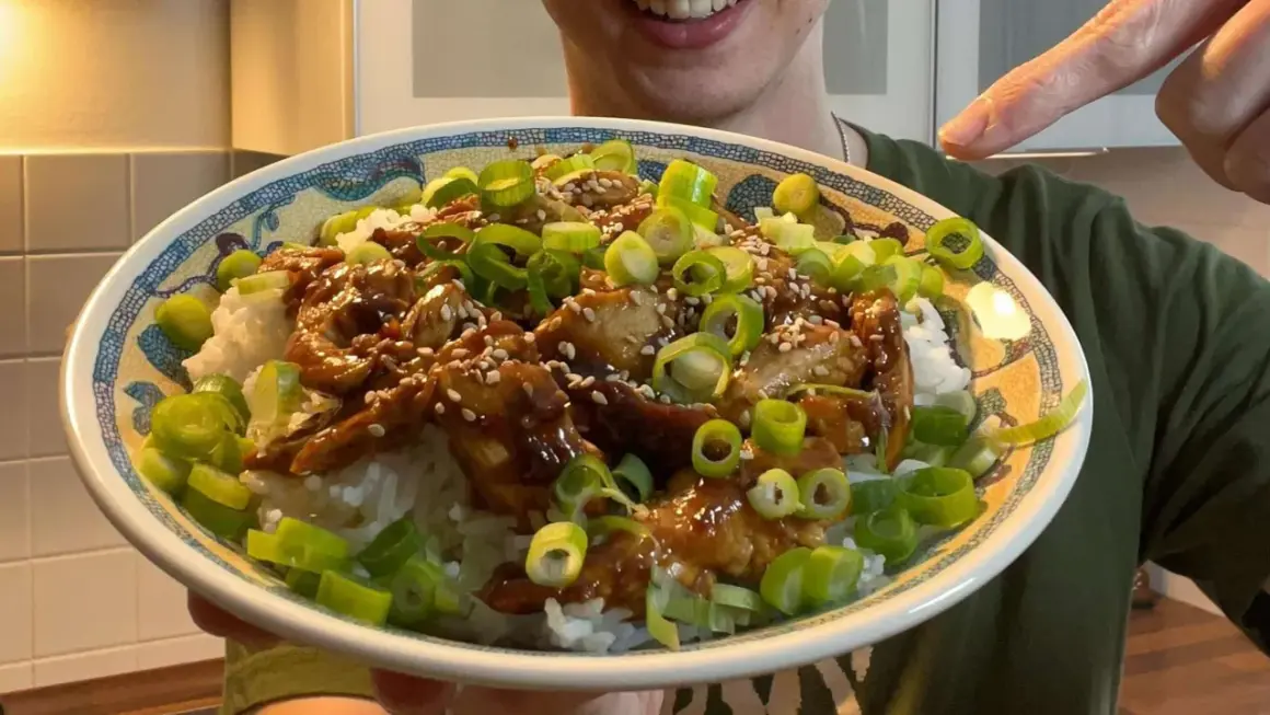 Leckeres Hähnchen Teriyaki Rezept: saftiges Hähnchen in Teriyaki-Sauce auf Reis, garniert mit Frühlingszwiebeln und Sesam.