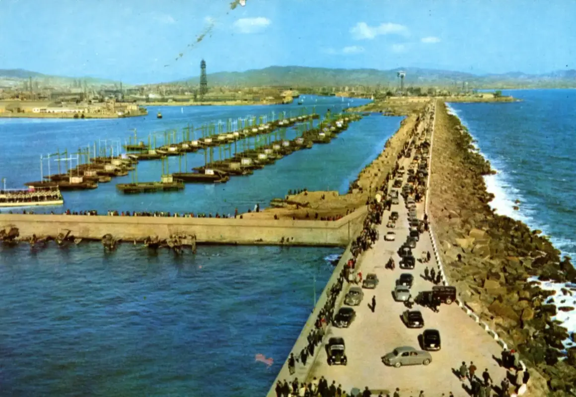 El rompeolas de Burela, con barcos alineados y coches circulando, protege la costa de las olas.