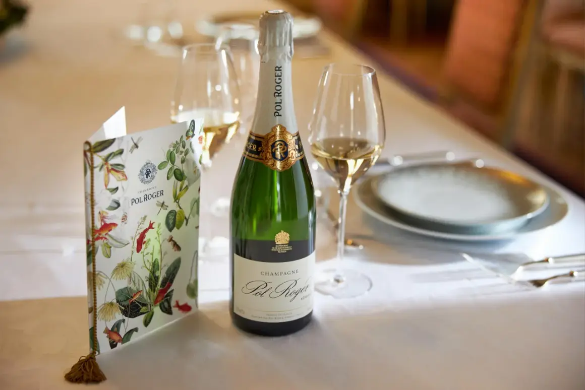 Eine Flasche Pol Roger Champagner steht bereit, daneben ein Glas und eine Speisekarte mit floralem Muster.