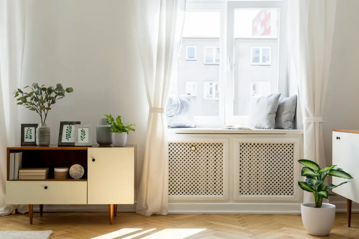 Elegancka osłona kaloryfera pod oknem, z ażurowym wzorem, stanowi stylowe rozwiązanie, jak zasłonić kaloryfer pod oknem, jednocześnie dodając wnętrzu uroku.
