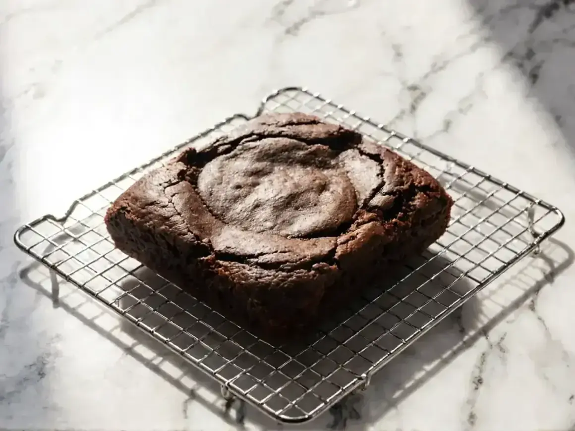 Idealny brownie, lekko popękany na wierzchu, stygnie na metalowej kratce.