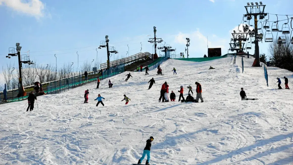 Zimowe atrakcje dla dzieci na Mazowszu: stok narciarski z wyciągiem, na którym bawią się rodziny, ucząc się jeździć na nartach i snowboardzie.