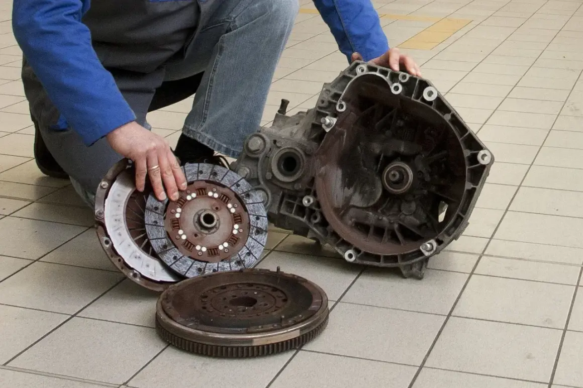 Mechanik pokazuje rozłożony zestaw sprzęgła i skrzynię biegów. Uszkodzony wysprzęglik objawy mogą być różne, ale ten element jest kluczowy.