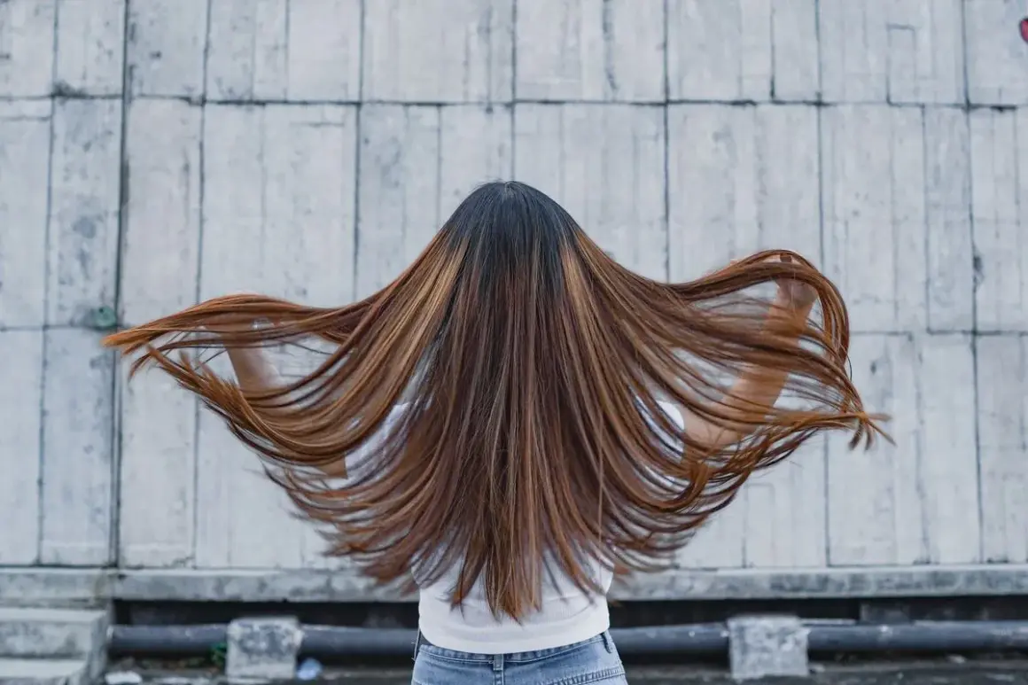 Lange, braune Haare mit honigfarbenen Strähnen, die sich im Wind bewegen. Ein perfekter Look für die sommer trend haarfarben.