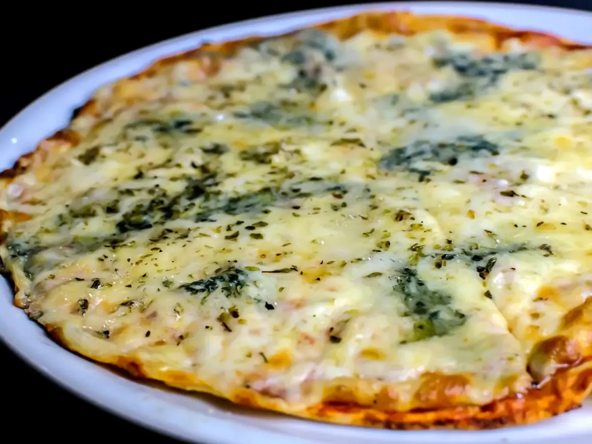 Eine köstliche quattro formaggi pizza mit geschmolzenem Käse und Kräutern, serviert auf einem weißen Teller.