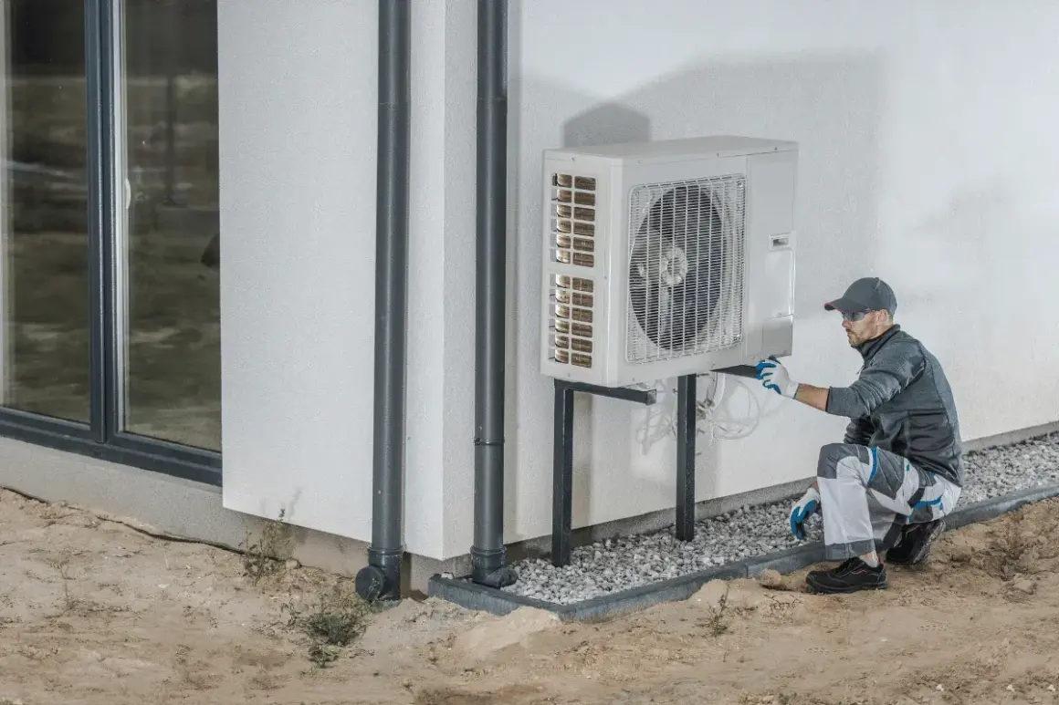 Tecnico che installa una pompa di calore esterna, un sistema efficiente per riscaldare e raffreddare la casa.