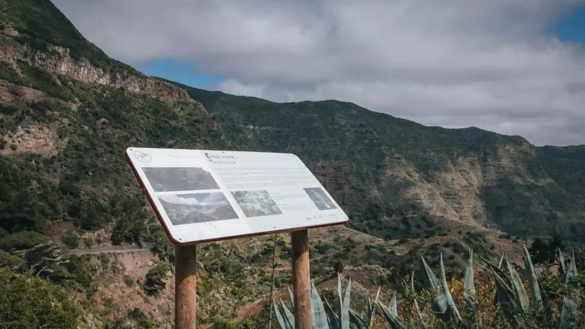 Panel informativo en el mirador de Carboneras, con vistas a un valle montañoso cubierto de vegetación.