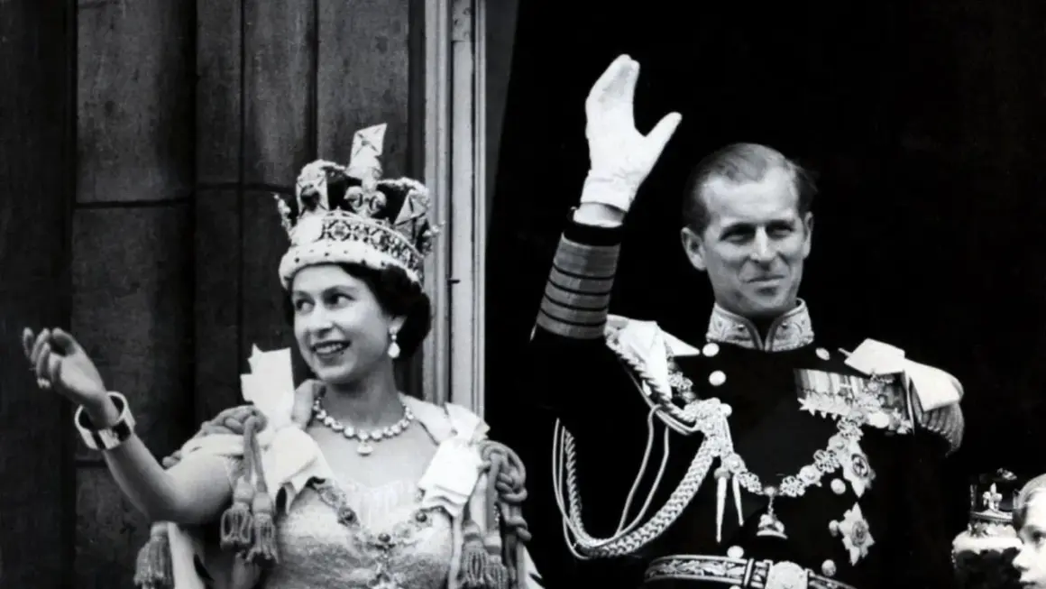 La reina Isabel II, con su corona, y el príncipe Felipe saludan tras su coronación.