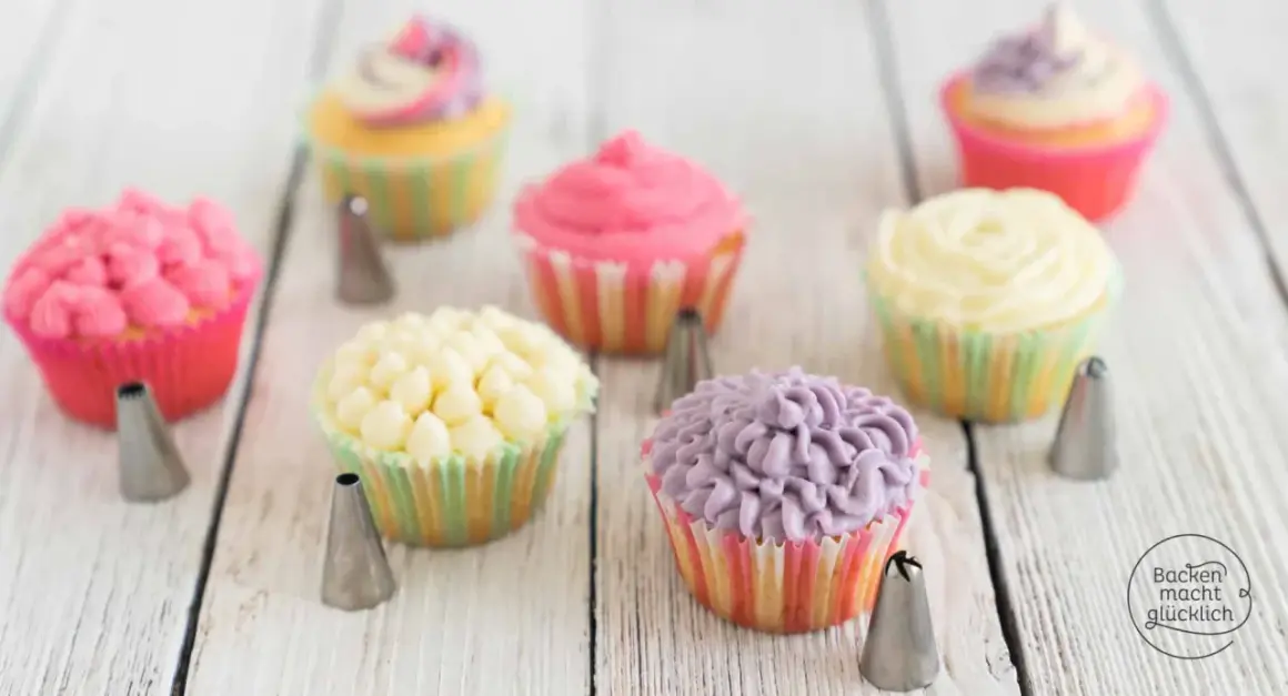 Bunte Cupcakes mit verschiedenen **cupcake topping** Mustern, umgeben von Spritztüllen.