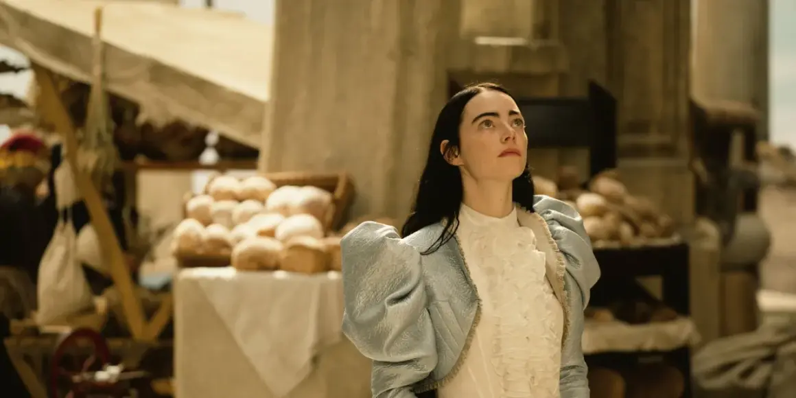 Bella Baxter blickt hoffnungsvoll gen Himmel, während sie auf dem Markt steht. Ein Bild, das Lust macht, "Poor Things" zu streamen.