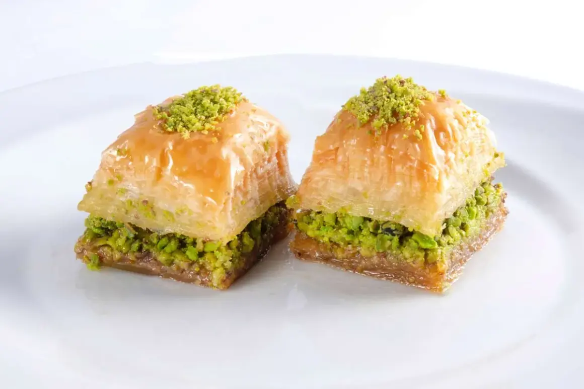 Zwei süße, schichtweise gebackene Teigstücke mit Pistazienfüllung und Sirup. Das ist Baklava, ein köstliches Dessert.