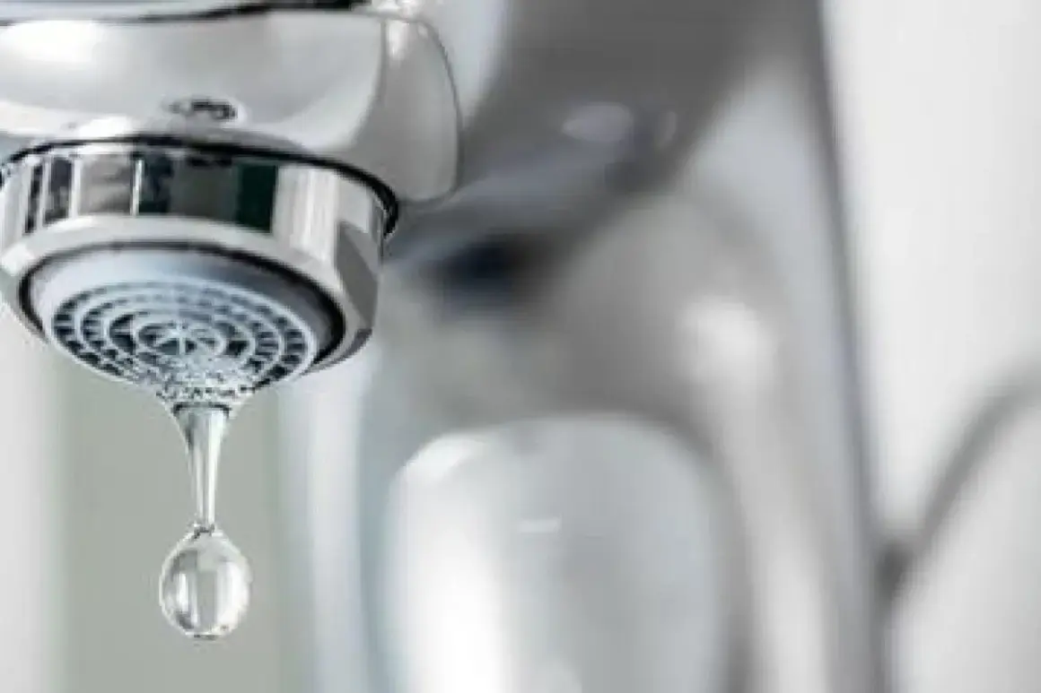 Goutte d'eau tombant d'un robinet qui goutte. Le chrome brillant du robinet contraste avec la goutte d'eau transparente.