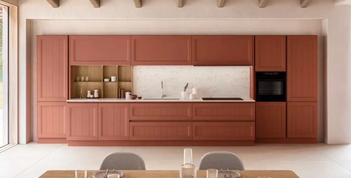 Cuisine moderne avec des armoires couleur terre cuite, un évier, un four et des chaises grises.