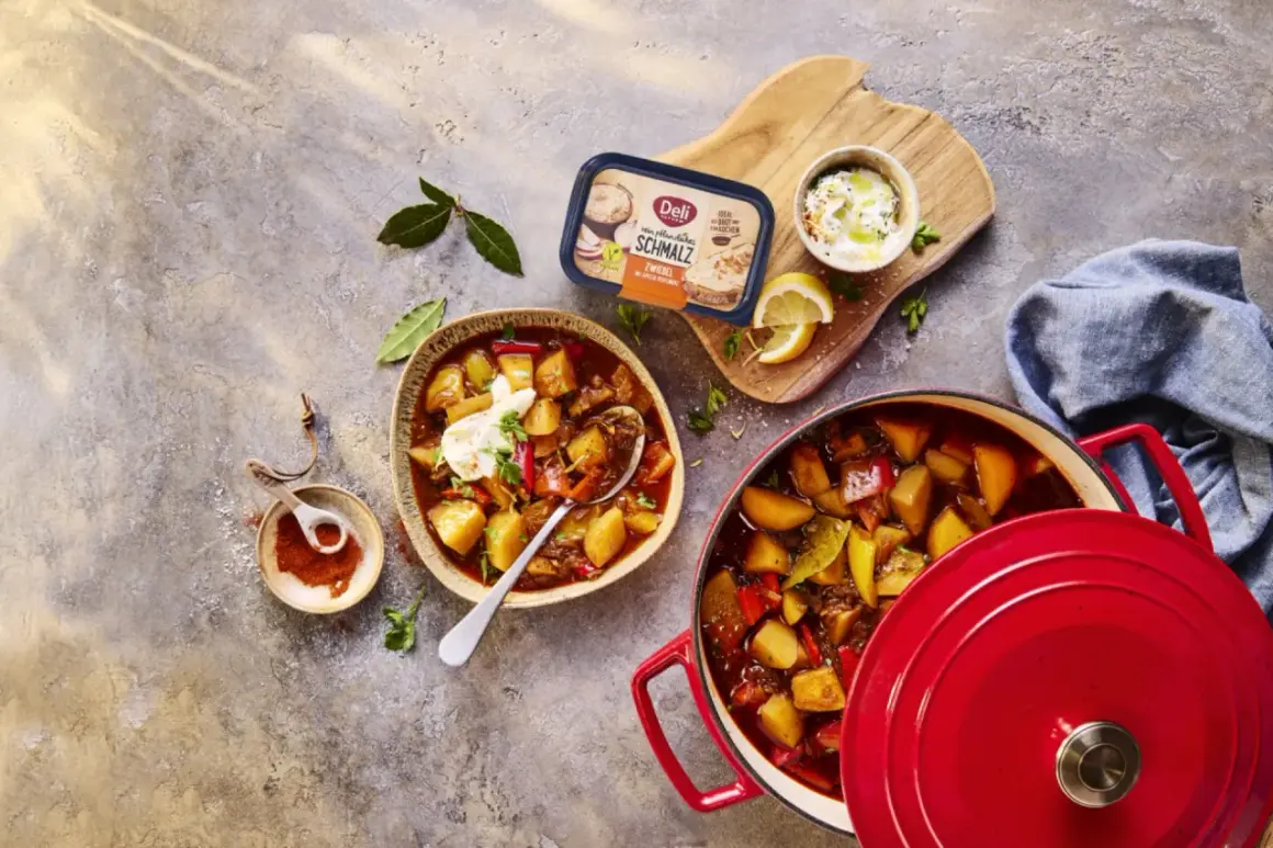 Herzhaftes Gulasch mit Kartoffeln und Paprika, perfekt zum Schmoren lassen. Daneben ein Becher Schmalz und Gewürze.