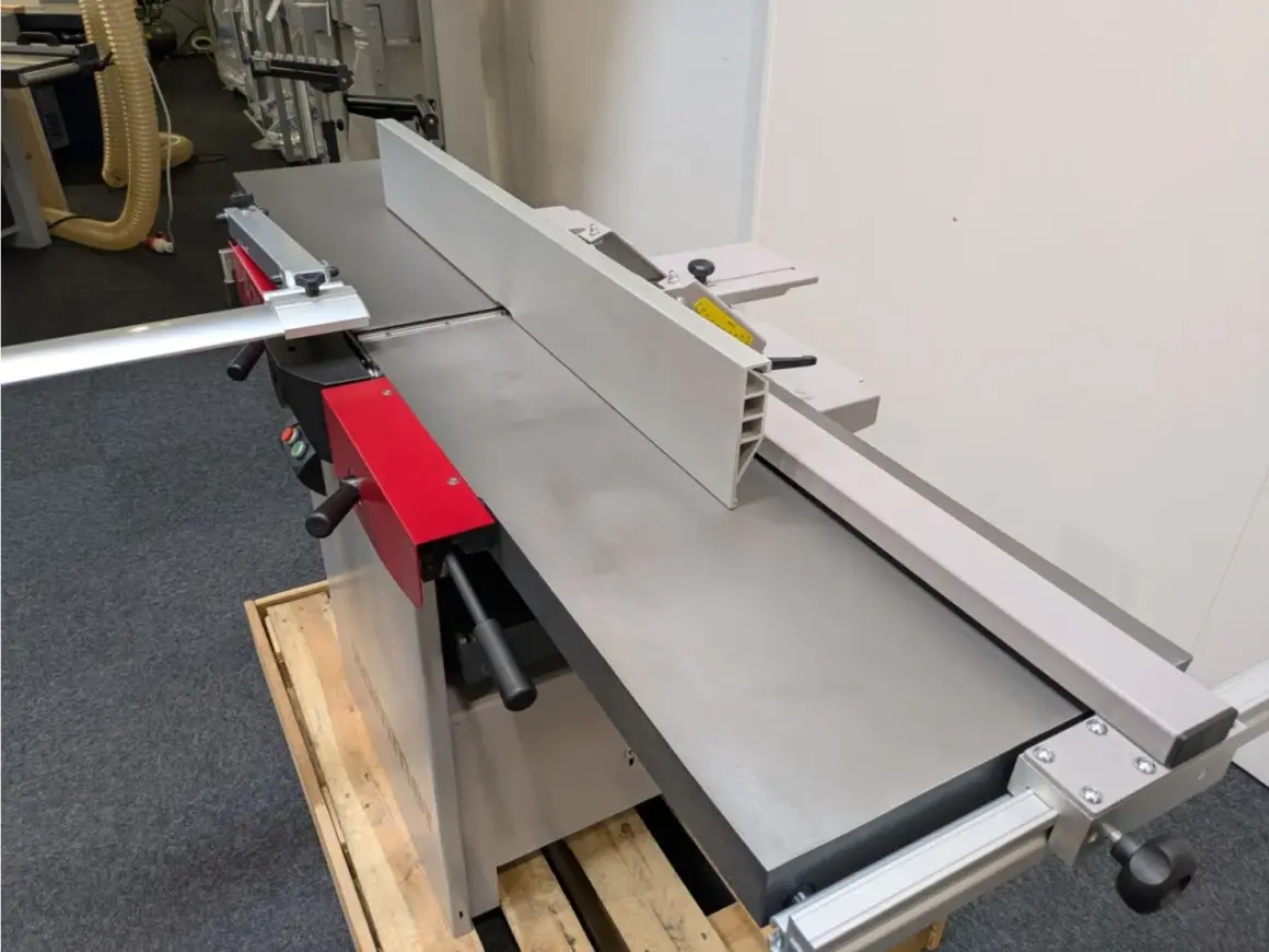 Détail d'une dégauchisseuse Hammer C3 41, machine à bois professionnelle avec son guide et ses poignées rouges.