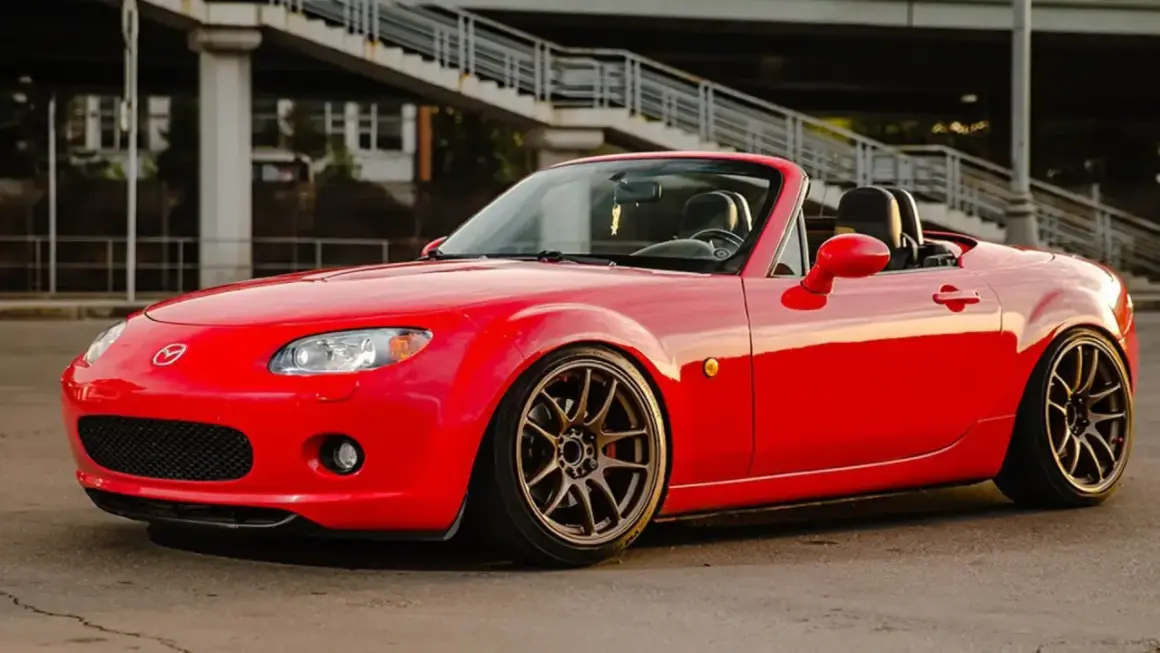 Mazda MX-5 rouge rutilante, parfaite pour un jeune permis rêvant de sa première voiture sport.