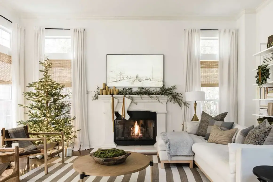 Cozy living room with a lit Christmas tree and fireplace, showcasing elegant holiday mantel ideas with stockings and greenery.