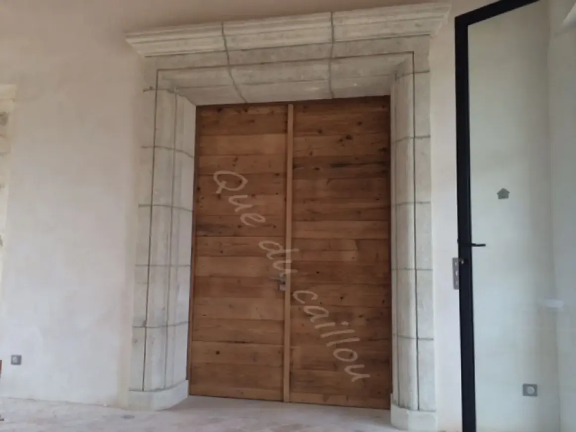 Un encadrement de porte en pierre, avec une couleur différente de la porte en bois brut.