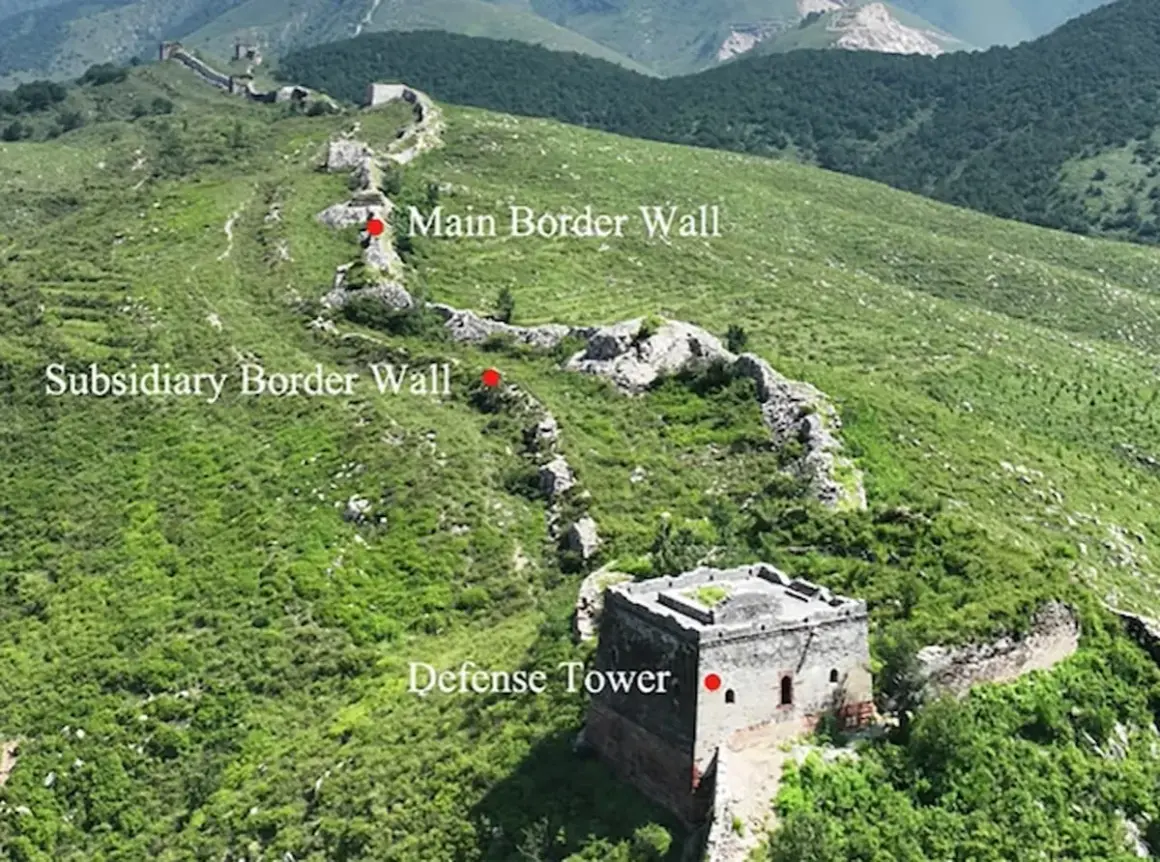 La muralla china se extiende por colinas verdes, con una torre de defensa y muros principales y subsidiarios.
