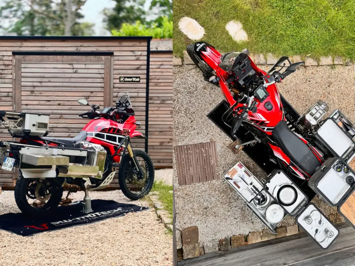 Una moto trail roja lista para la aventura, con maletas y equipo de camping.
