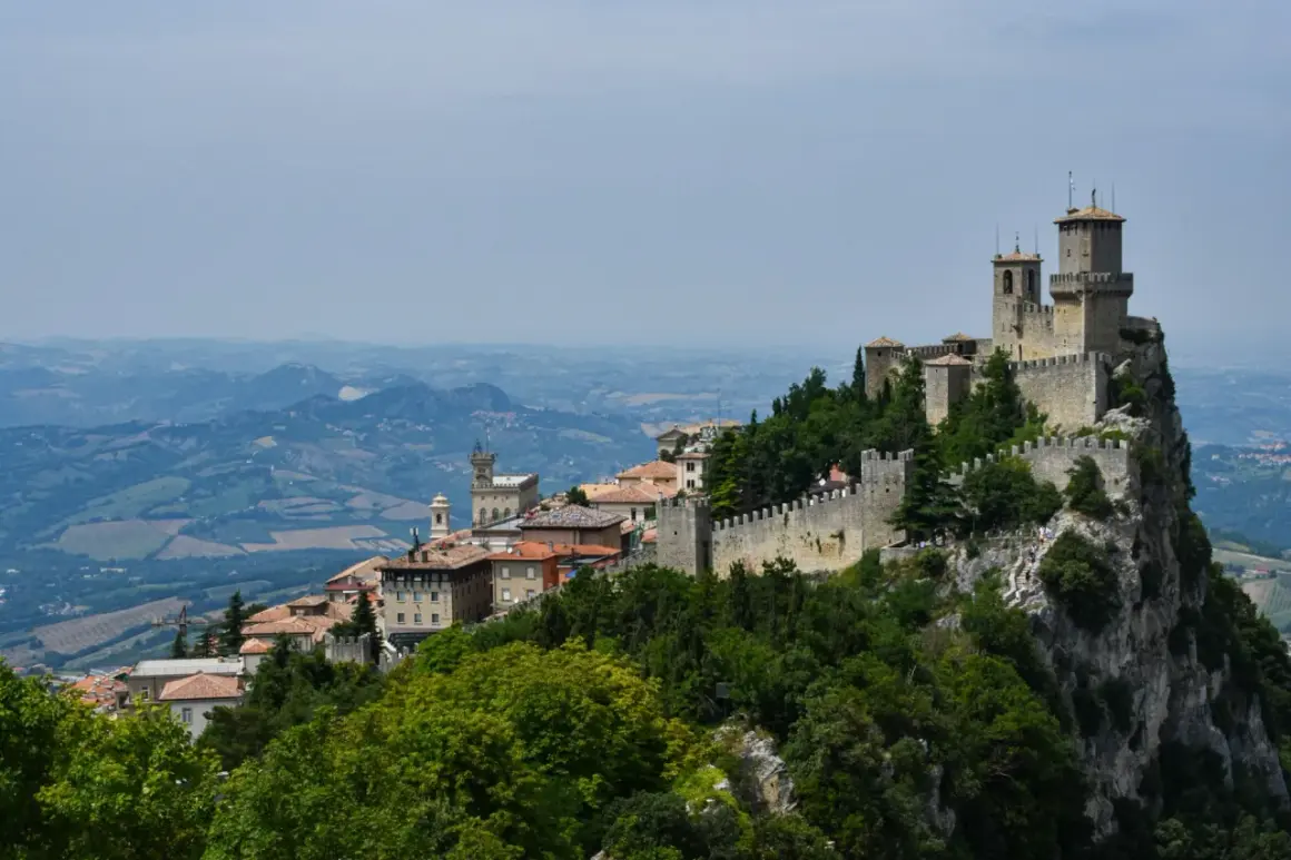 San Marino na terytorium Włoch, z górującymi wieżami i kamiennymi murami, wznosi się dumnie na skalistym szczycie, otoczone zielonymi wzgórzami.