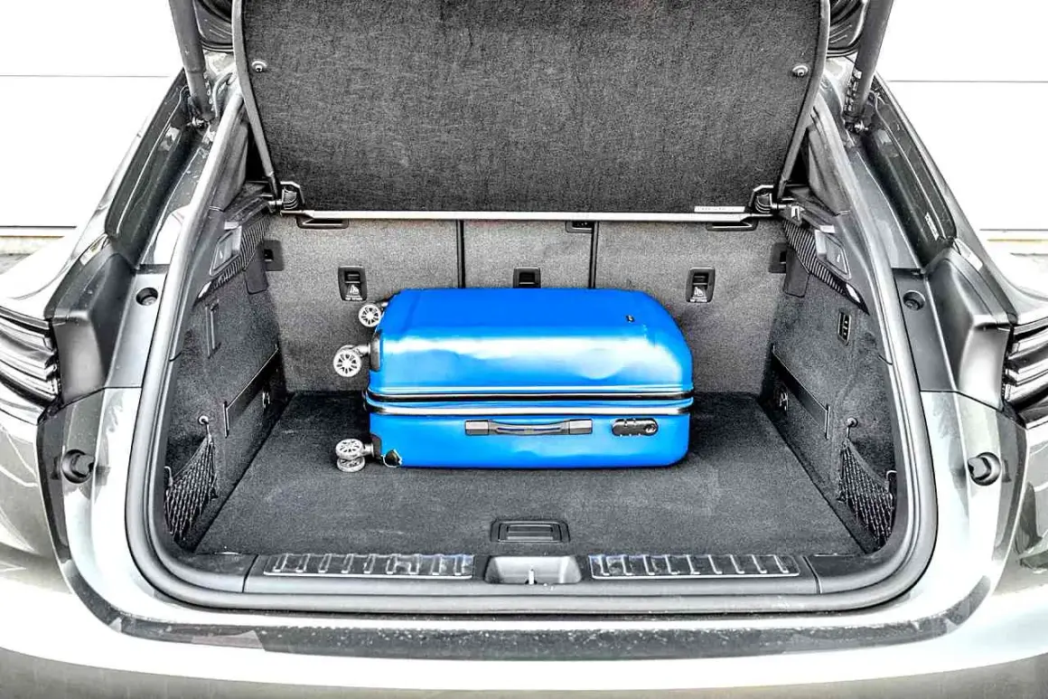 Bagażnik Porsche Macan, z niebieską walizką, pokazuje, jak kompaktowe są jego wymiary.