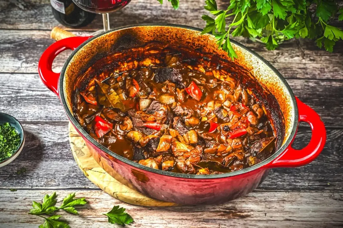 Herzhaftes Gulasch-Rezept in einem roten Bräter, mit zarten Fleischstücken, Paprika und Zwiebeln, bereit zum Servieren.
