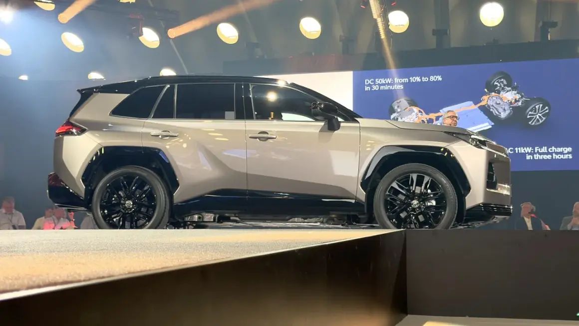 Nowe Toyota RAV4 opinie: elegancki SUV na scenie, z ekranem pokazującym ładowanie.